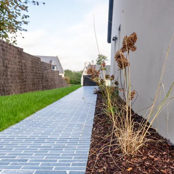 Allée de jardin pavée accompagnée de parterres plantés, réalisée par un paysagiste à Rennes