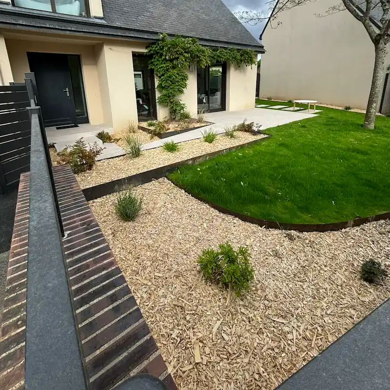 Aménagement paysager sur-mesure avec terrasse béton et plantations à Betton.