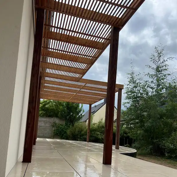 Conception de pergola en bois sur-mesure avec toiture à lames sur terrasse dallée à Rennes