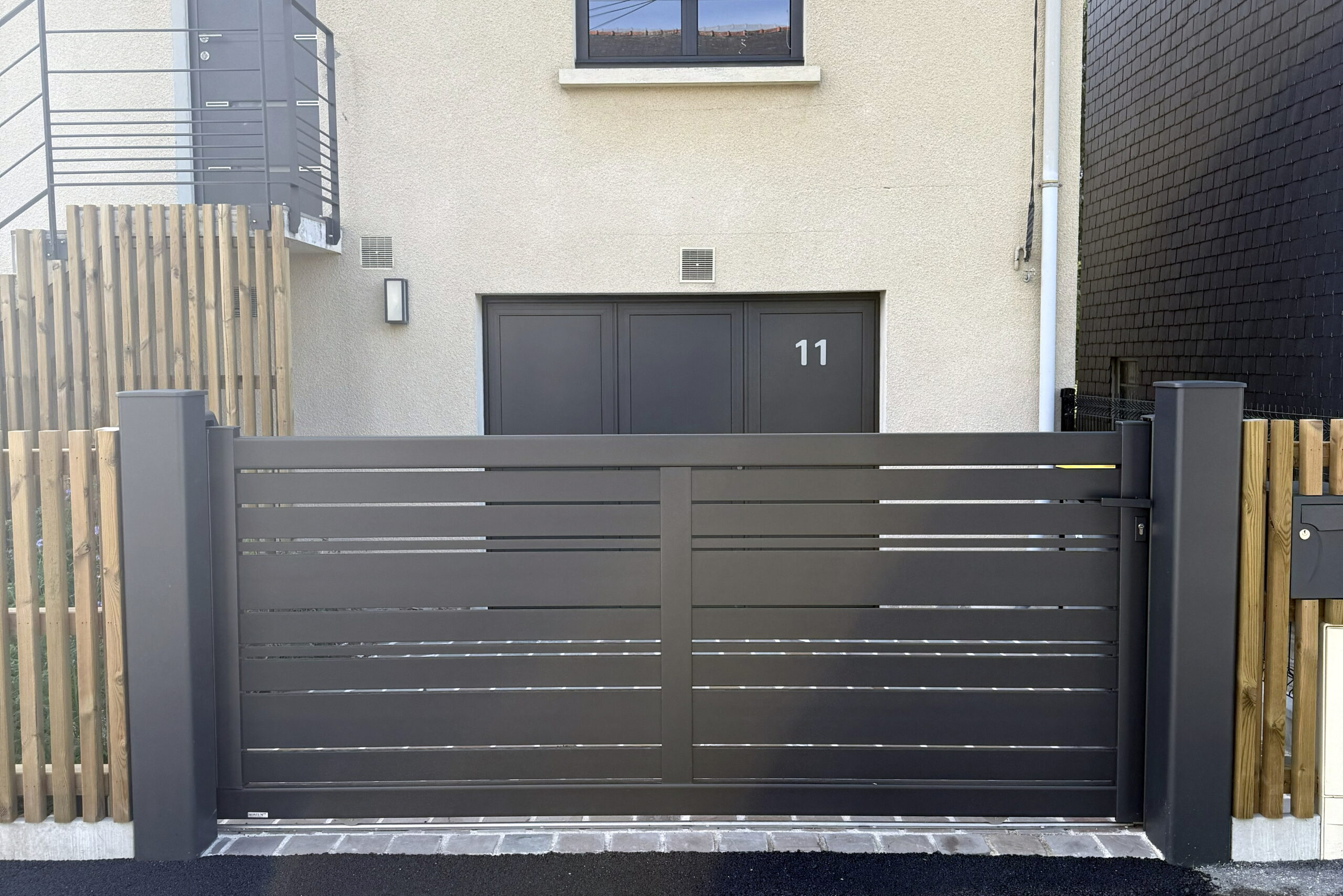 Portail alu anthracite coulissant et clôture bois pour l'intimité à Rennes par Fred Toma.